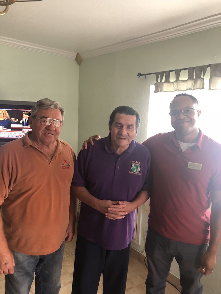 Three men posing together indoors with smiles.