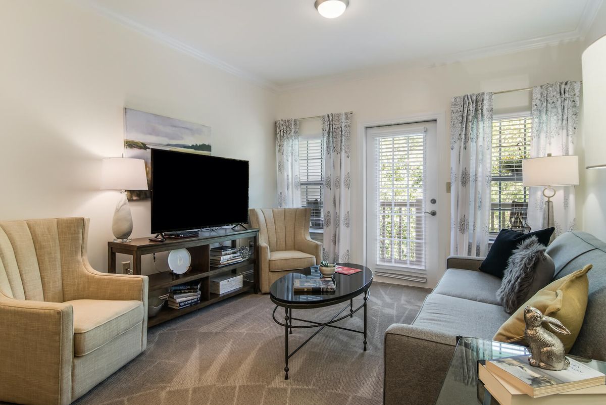 A cozy living room featuring modern furniture and a large TV.