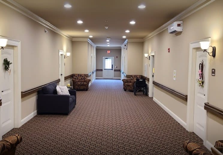 A well-lit hallway with sofas and carpeted flooring.
