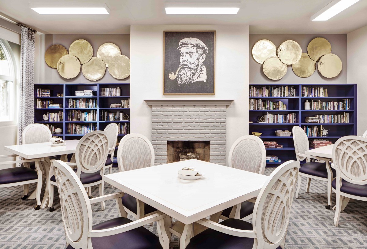 A cozy library room featuring bookshelves, a fireplace, and seating area.