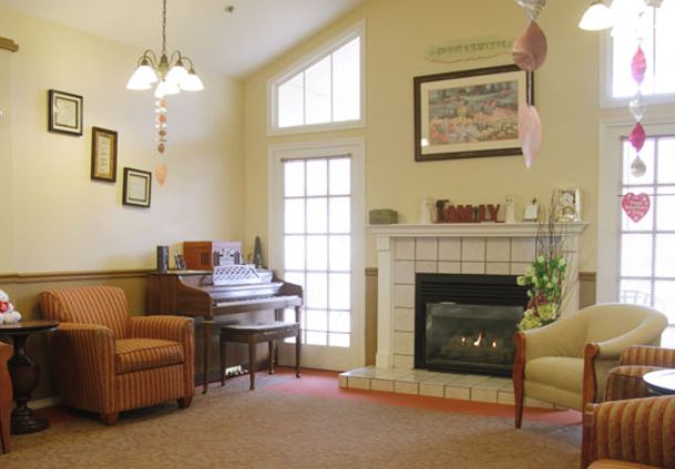 A cozy living room featuring a fireplace, piano, and comfortable seating.