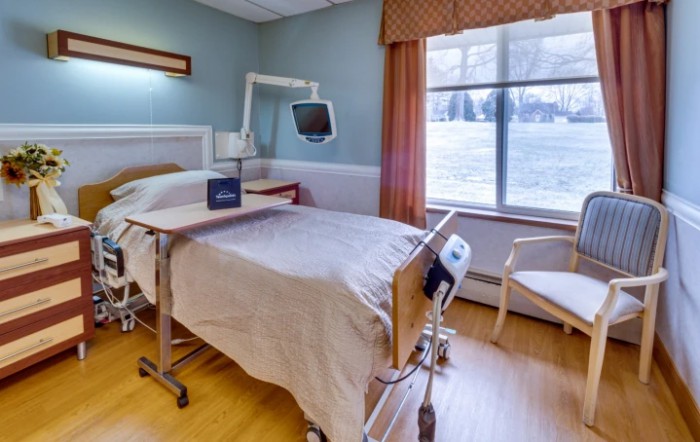 A hospital room with a single bed and medical equipment by the window.