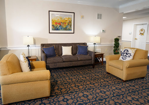 A cozy living room setup featuring a sofa and armchairs, complemented by a decorative painting and soft lighting.
