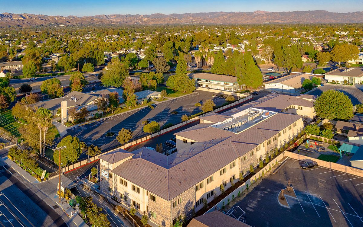 Aerial view of a residential area with buildings surrounded by trees on a sunny day.