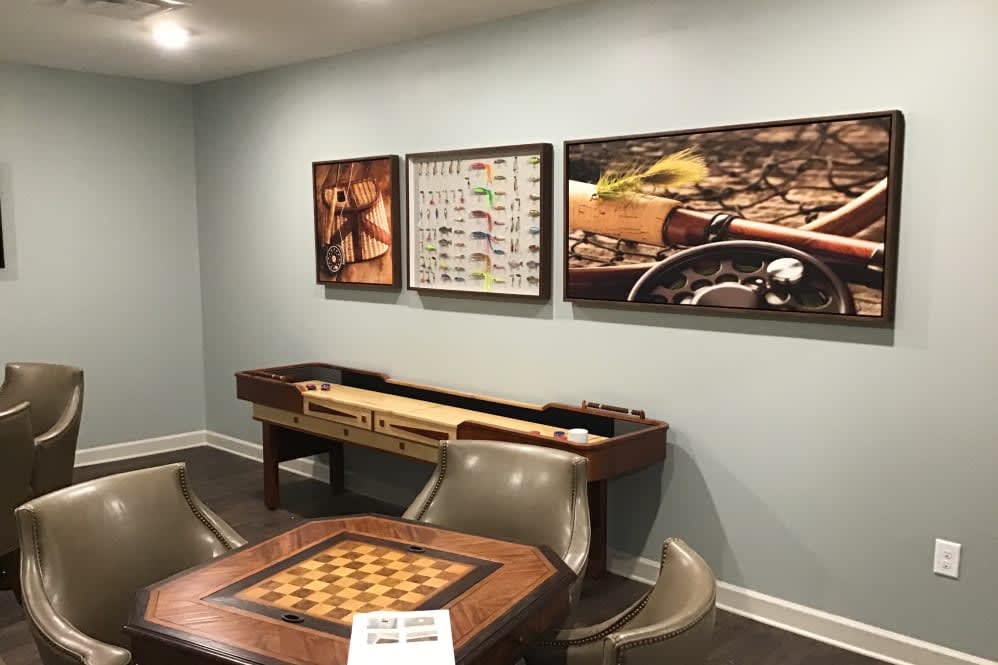 A cozy game room featuring a shuffleboard table, chess table, and wall art.