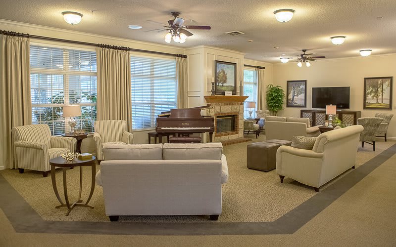 A cozy living room featuring a piano and fireplace, with comfortable sofas and elegant decor.