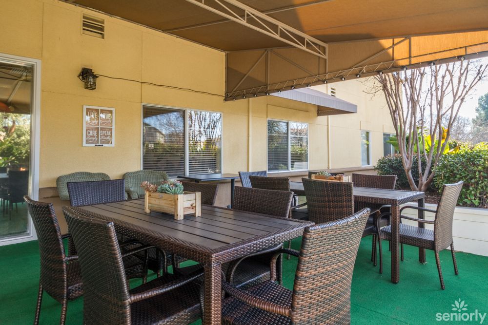 An outdoor patio area featuring wicker furniture with tables and chairs under a canopy.