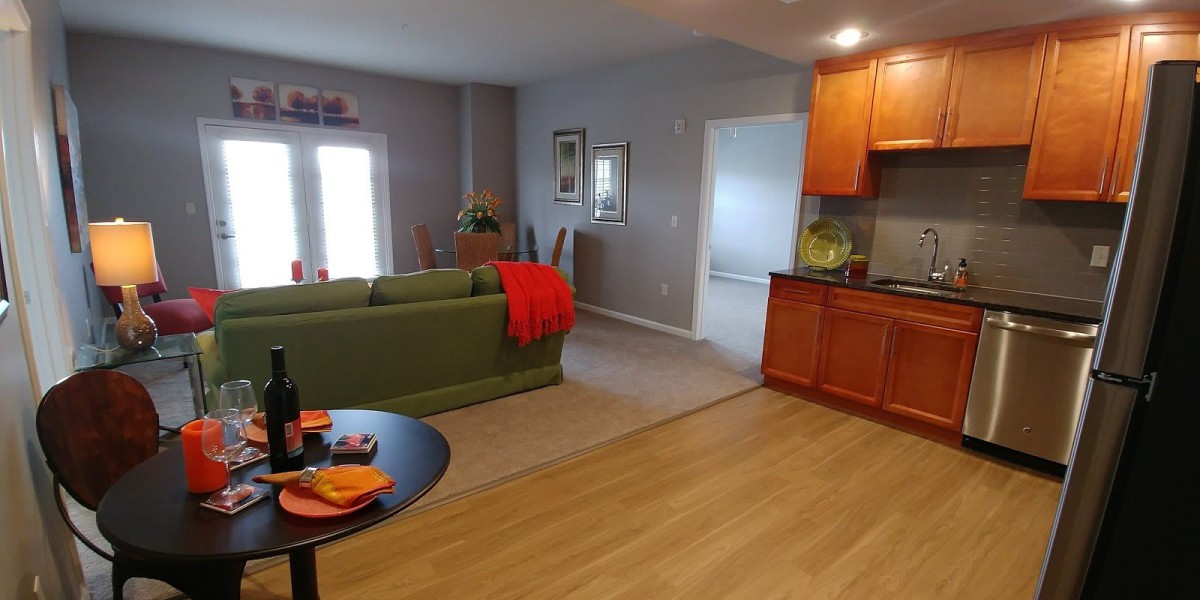 A cozy open-concept living room with a green sofa, adjoining kitchen, and dining area.