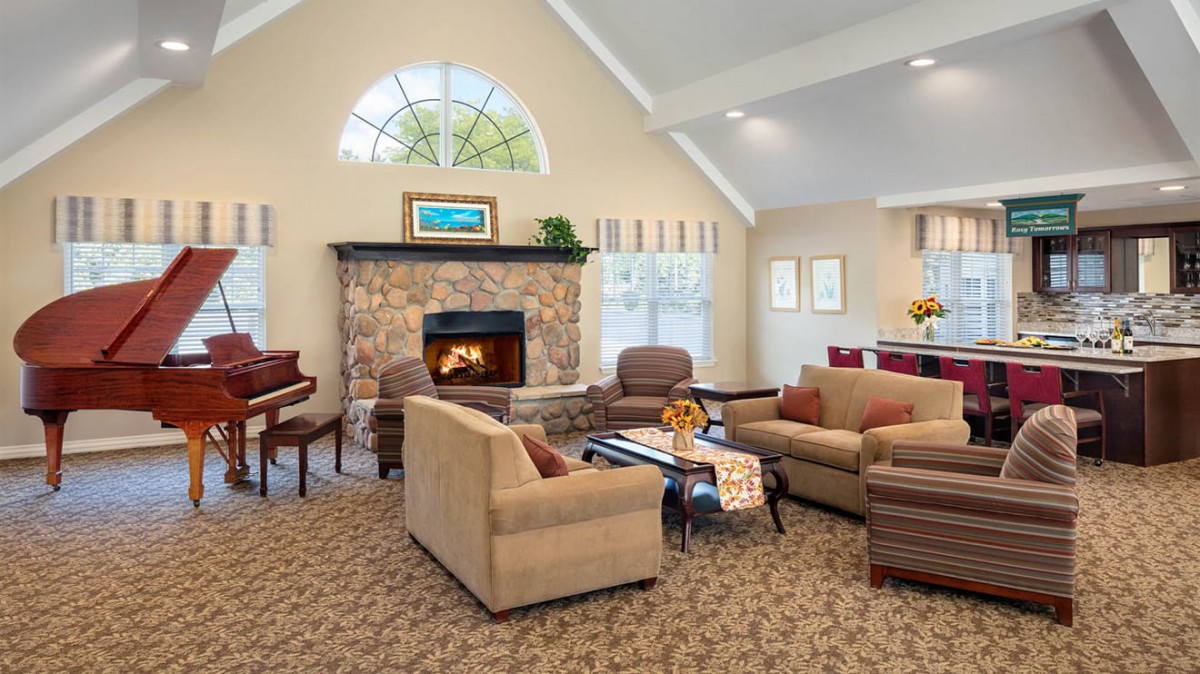 A cozy living room with a stone fireplace, comfortable sofas, and a piano.