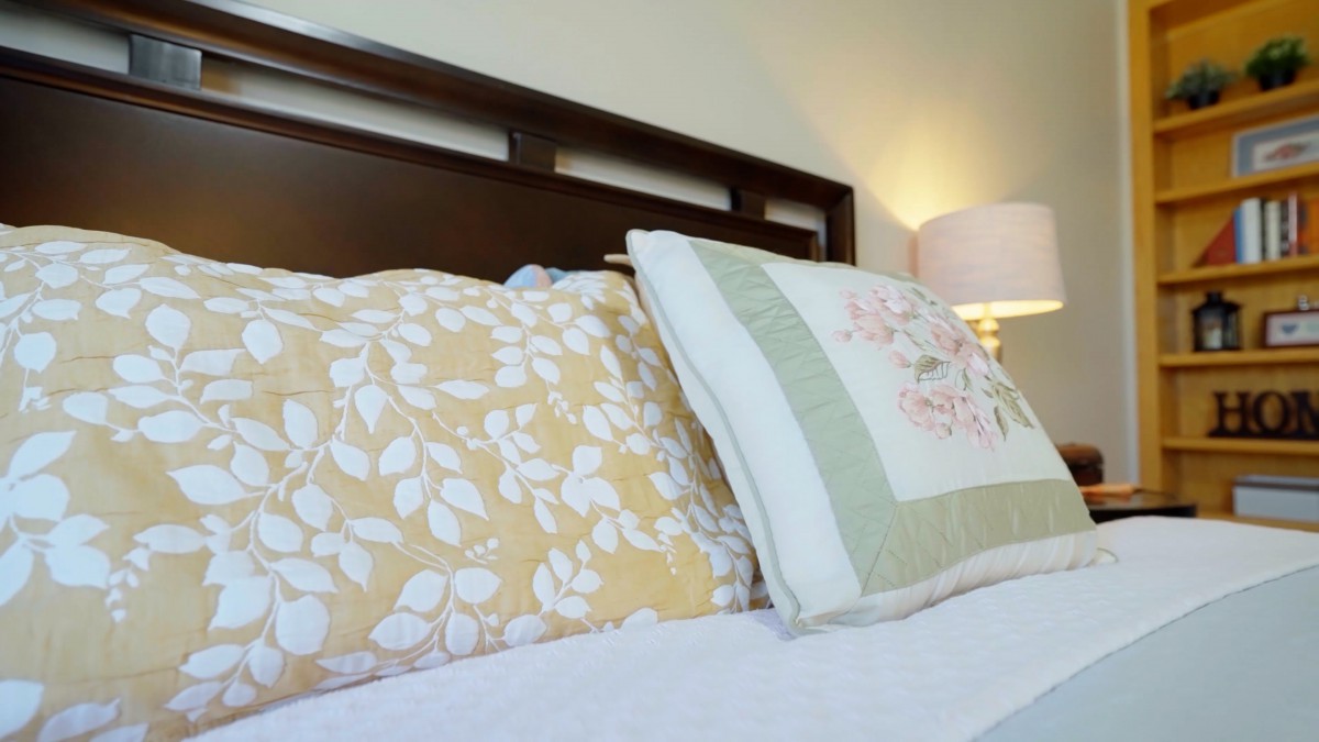 A cozy bedroom setting featuring decorative pillows and a wooden headboard.