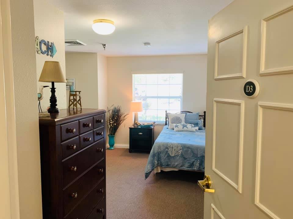 A cozy and well-lit bedroom with a bed, dresser, and lamp.