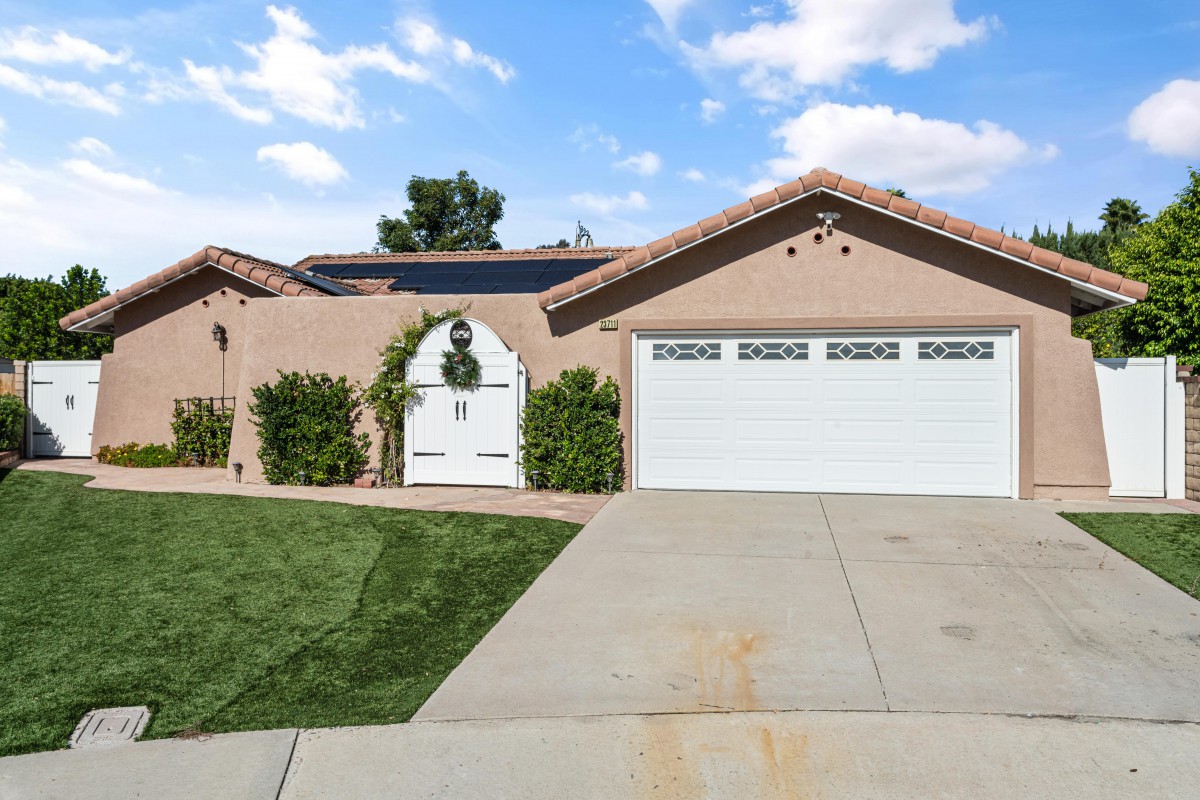 A suburban house with a two-car garage and solar panels on the roof.