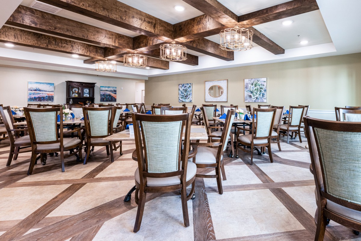 A spacious dining room featuring elegant chairs and tables, with wooden beams and chandeliers enhancing the ambiance.