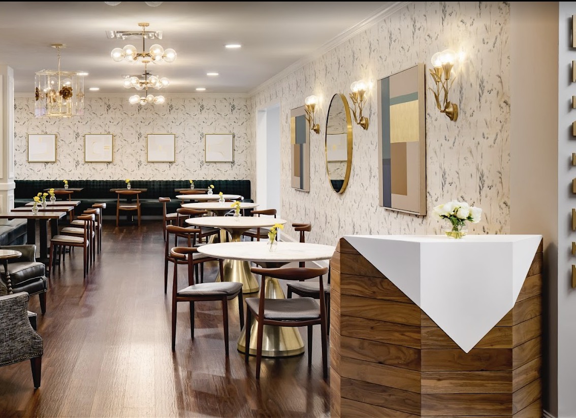 A modern restaurant interior with elegant tables and chairs, featuring stylish wall mirrors and lighting.