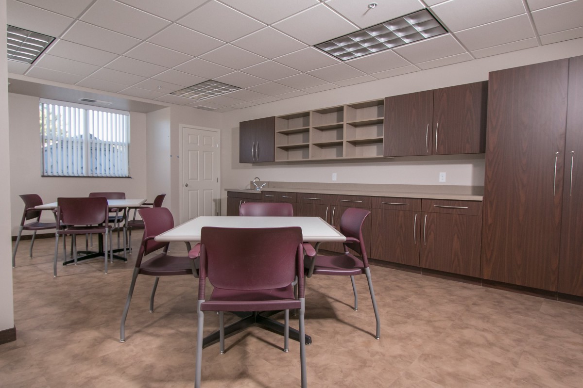 A clean and organized office meeting room with tables, chairs, and cabinets.