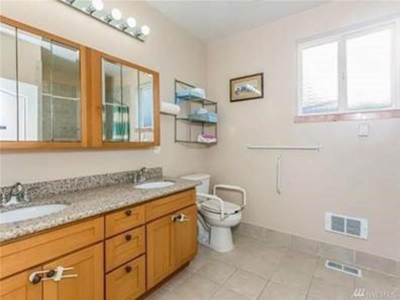 A clean and spacious bathroom with wooden cabinets, a granite countertop, and modern fixtures.