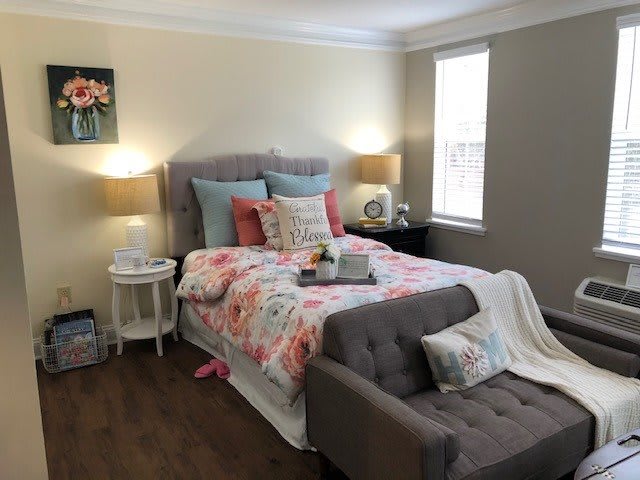 A cozy bedroom with a floral bedspread, decorative pillows, and warm lighting from bedside lamps.