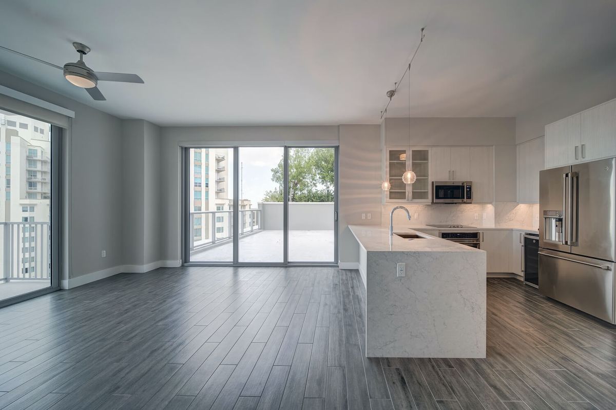 A modern open floor plan apartment featuring a kitchen and living area with access to a balcony.
