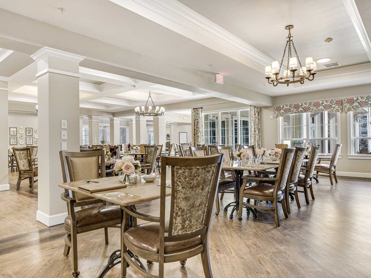 An elegantly decorated dining area with chandeliers and well-arranged tables and chairs.