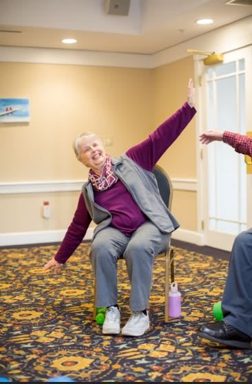 Seniors participating in a chair exercise class indoors.
