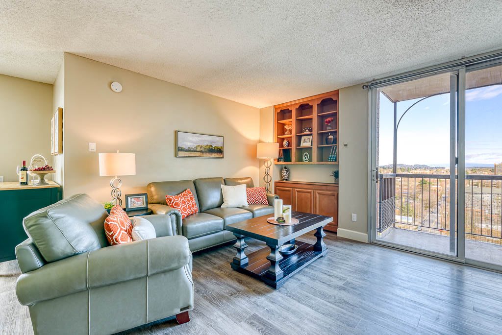 A cozy living room with a comfortable sofa, coffee table, and built-in shelves, featuring a balcony view.