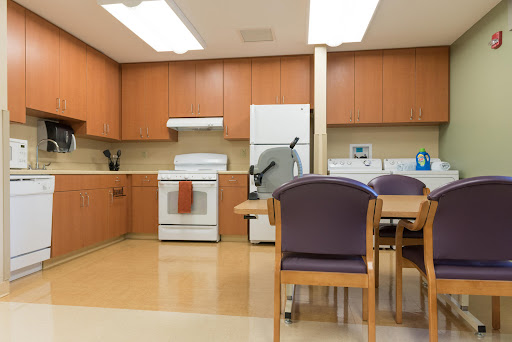 A modern kitchen and dining area featuring wooden cabinets, a stove, refrigerator, and a table with chairs.