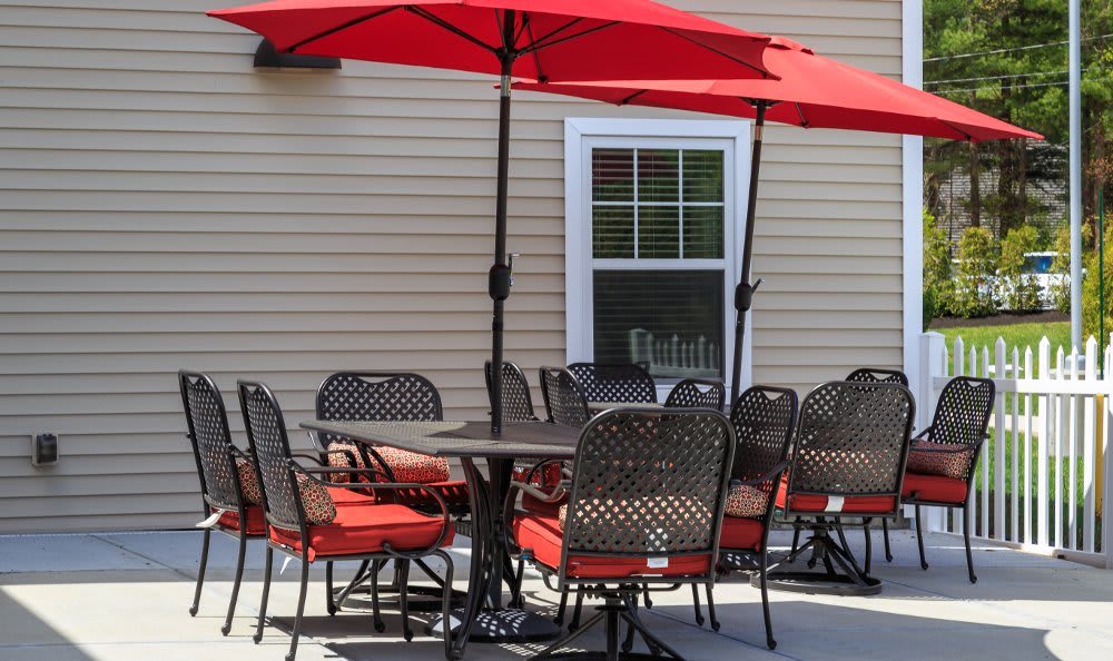 An outdoor patio with red umbrellas and a dining set.