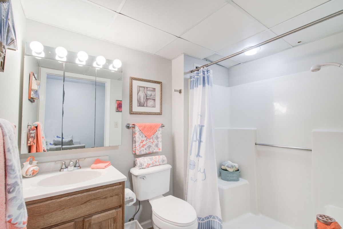 A well-lit bathroom with a shower, toilet, and sink.