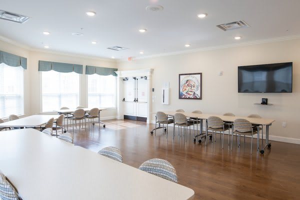 A bright, empty conference room with tables and chairs arranged neatly.