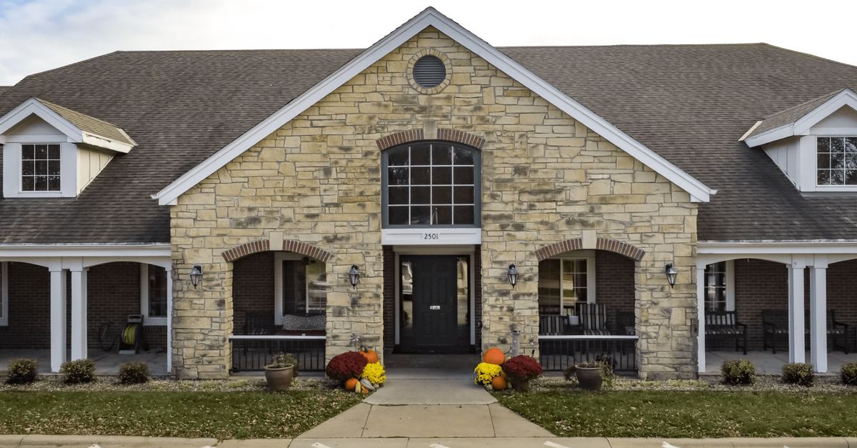 A stone building with a central entrance, adorned with autumn decorations and symmetrical windows.