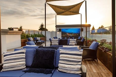 A cozy rooftop lounge with comfortable seating and a beautiful sunset view.