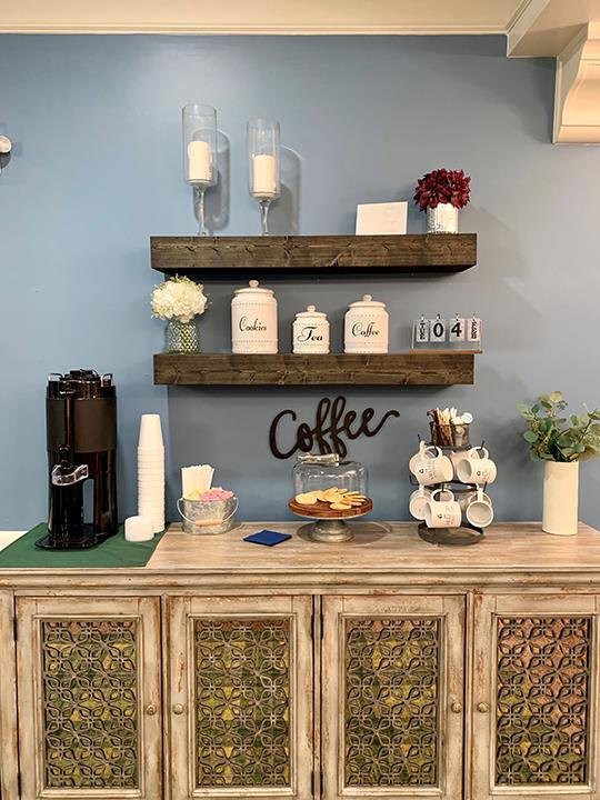 A cozy coffee station setup with decorative shelves, a coffee maker, mugs, and jars.