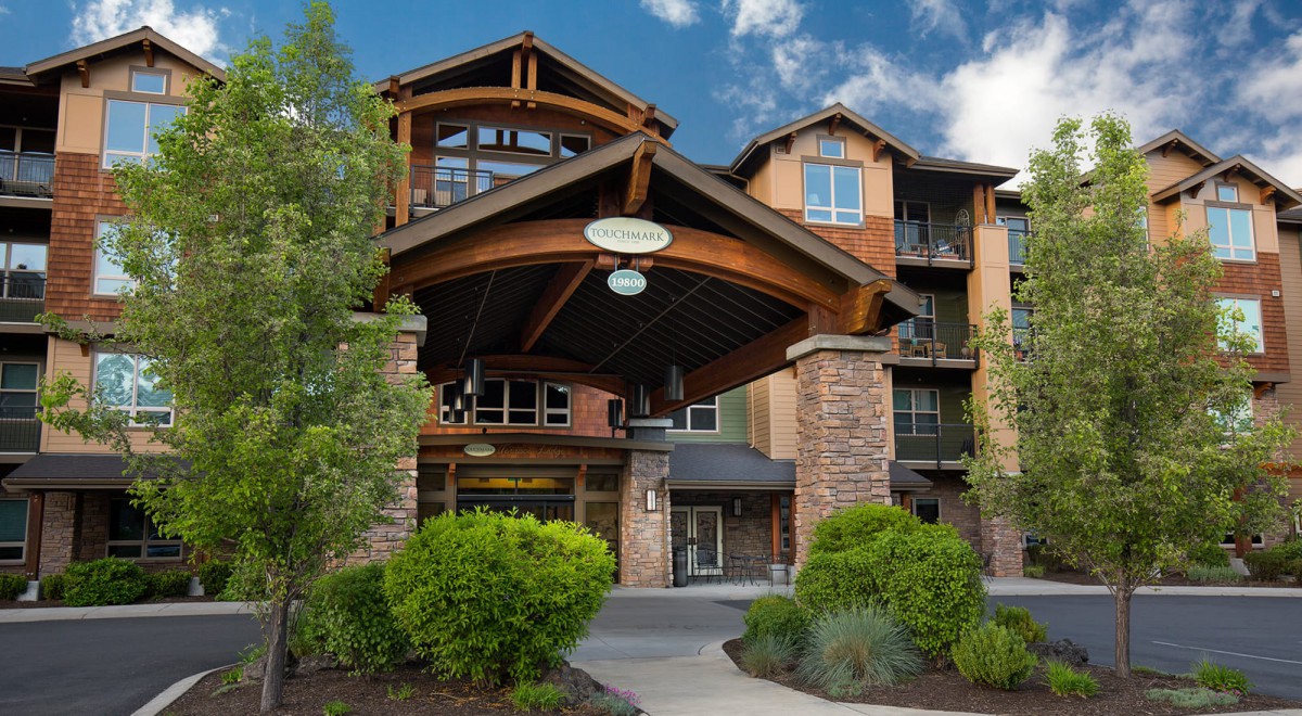 A beautiful hotel entrance featuring rustic architecture surrounded by lush greenery.