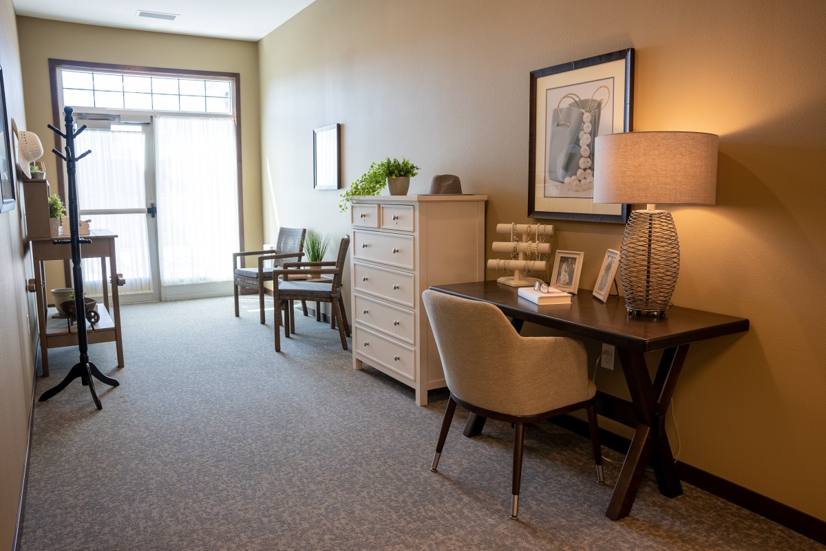 A well-furnished hallway with a desk, lamp, chairs, and decorative items.
