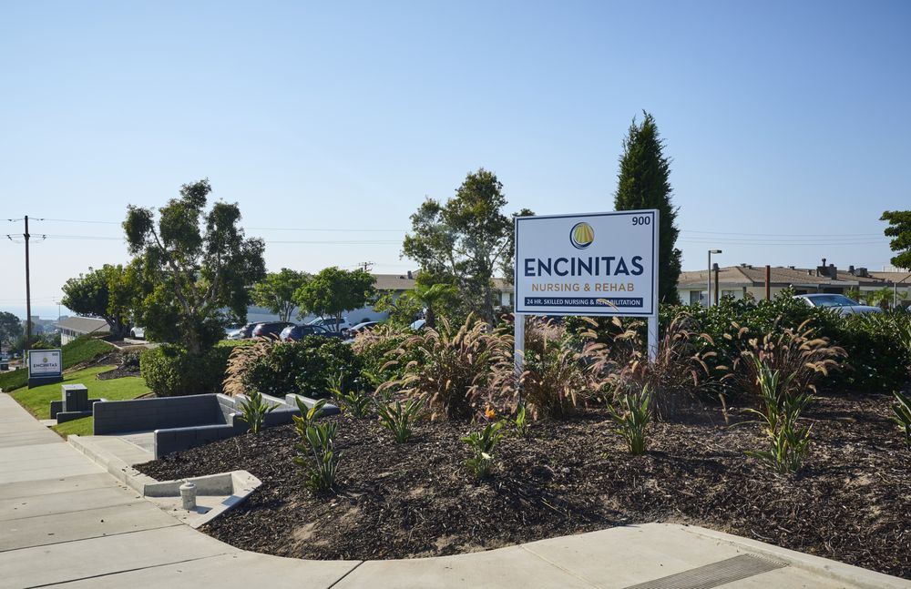 Sign at the entrance of a parking area in Encinitas, California, surrounded by landscaping and plants.