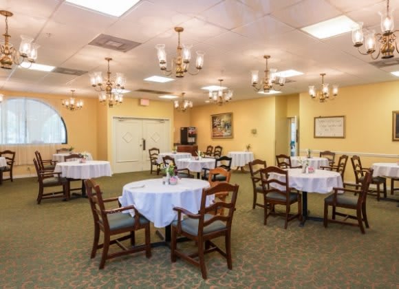 An elegantly set dining room with multiple tables and chandeliers.
