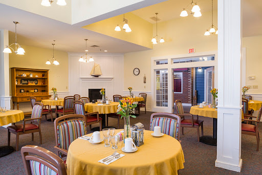 A bright and inviting dining area set for a meal, featuring yellow tablecloths and comfortable seating.