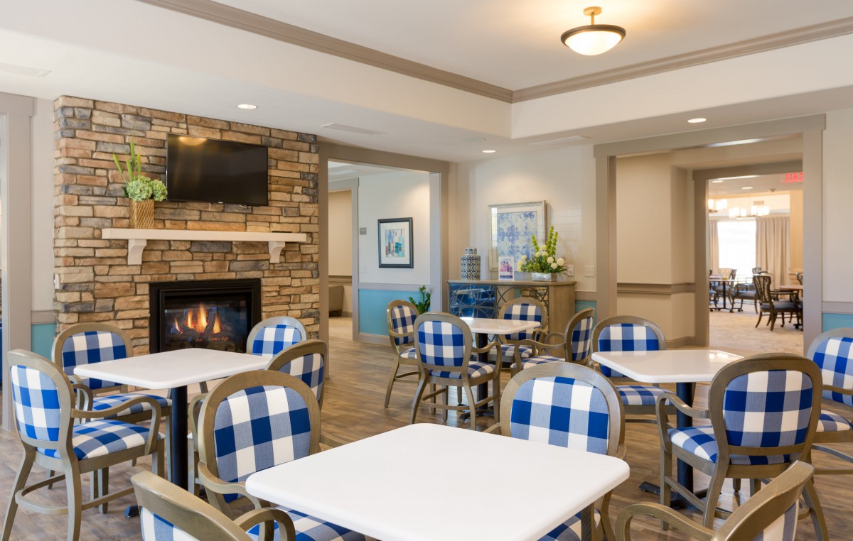 A cozy cafe interior with blue and white checkered chairs, a fireplace, and modern decor.