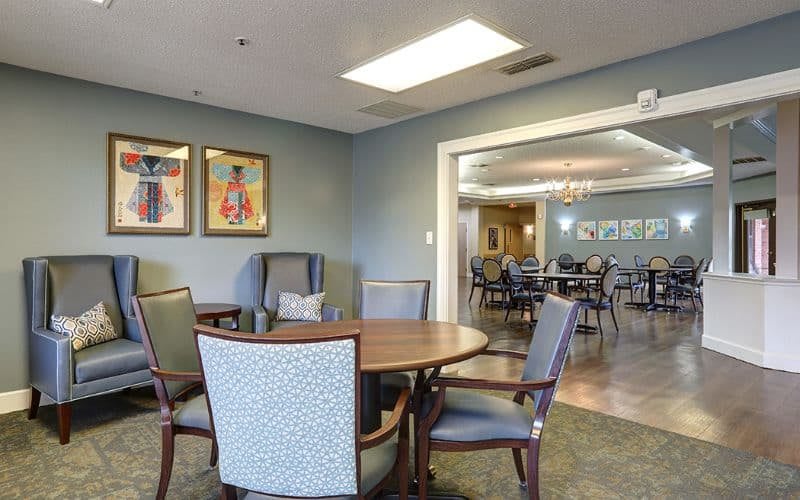 A spacious dining area with wooden tables and chairs, decorated with artwork and illuminated by soft lighting.