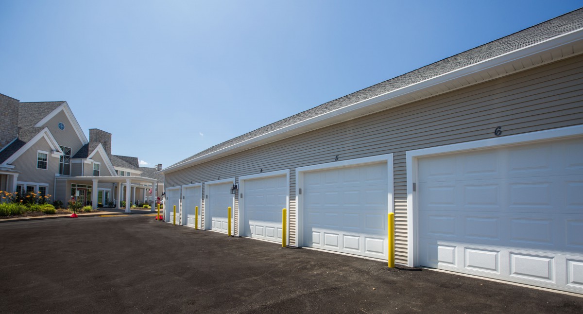 A row of storage garages with closed white doors under a clear blue sky.