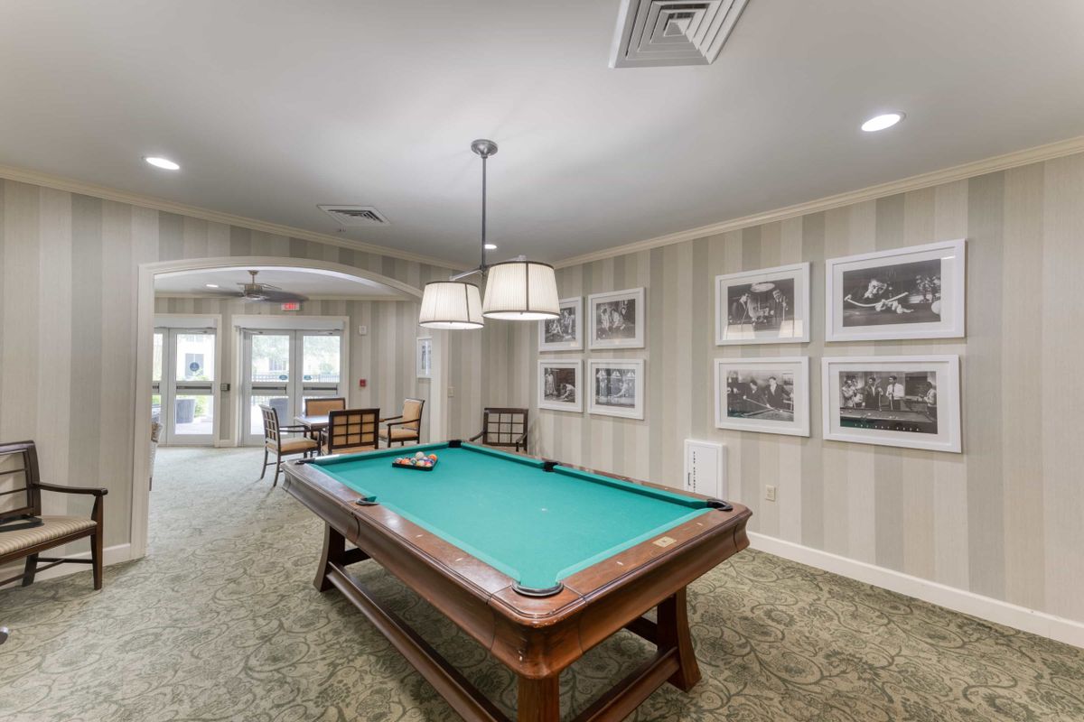 A recreation room featuring a pool table, comfortable seating, and framed wall art.