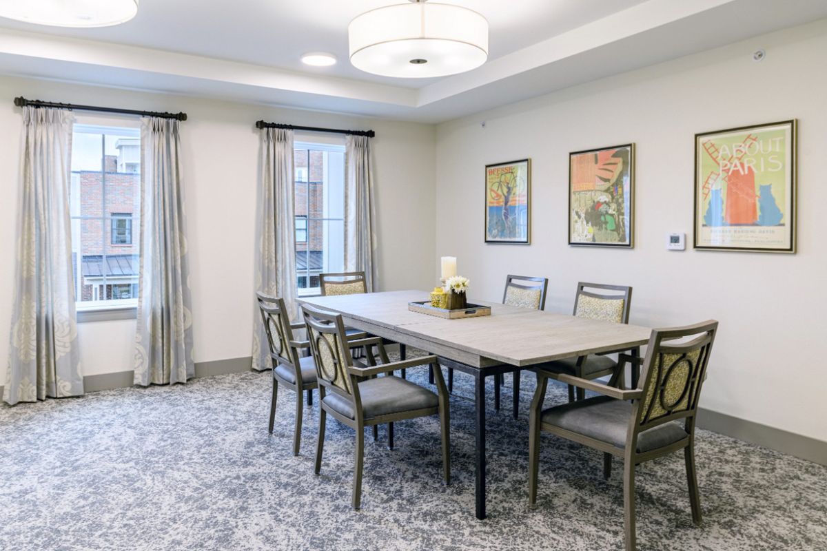 A modern dining room with a large table, elegant chairs, and decorative artwork on the walls.