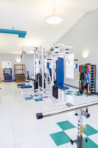 A well-equipped gym area featuring various strength training machines and rehabilitation tools.