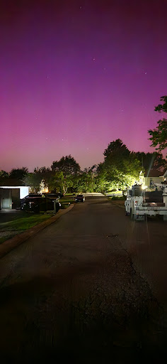 A serene night scene showcasing a quiet street illuminated by soft lights under a vibrant purple sky.