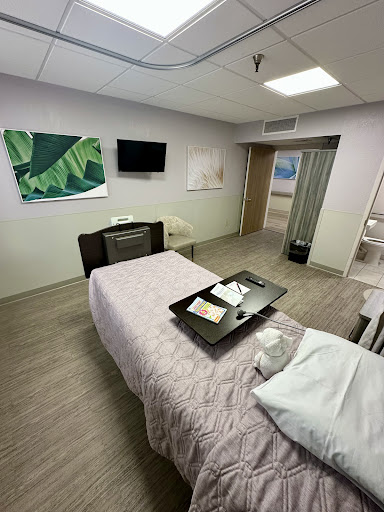 A modern and clean hospital patient room equipped with a bed, TV, and decorative artwork.