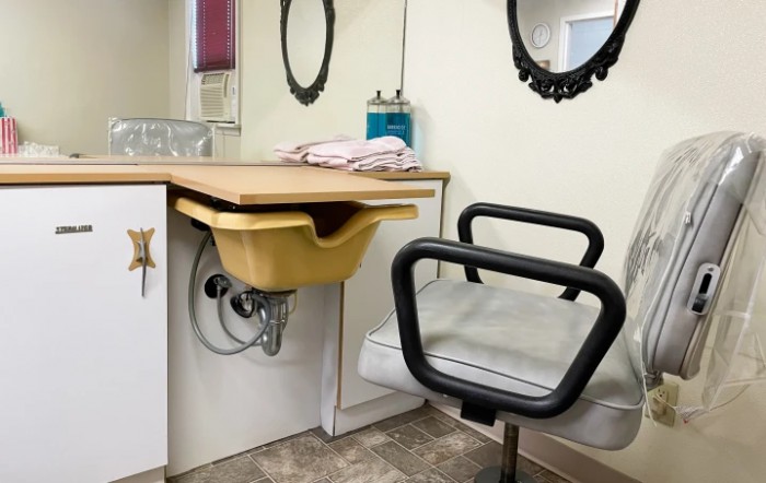 A cozy hair salon setup with a sink, mirror, and styling chair.