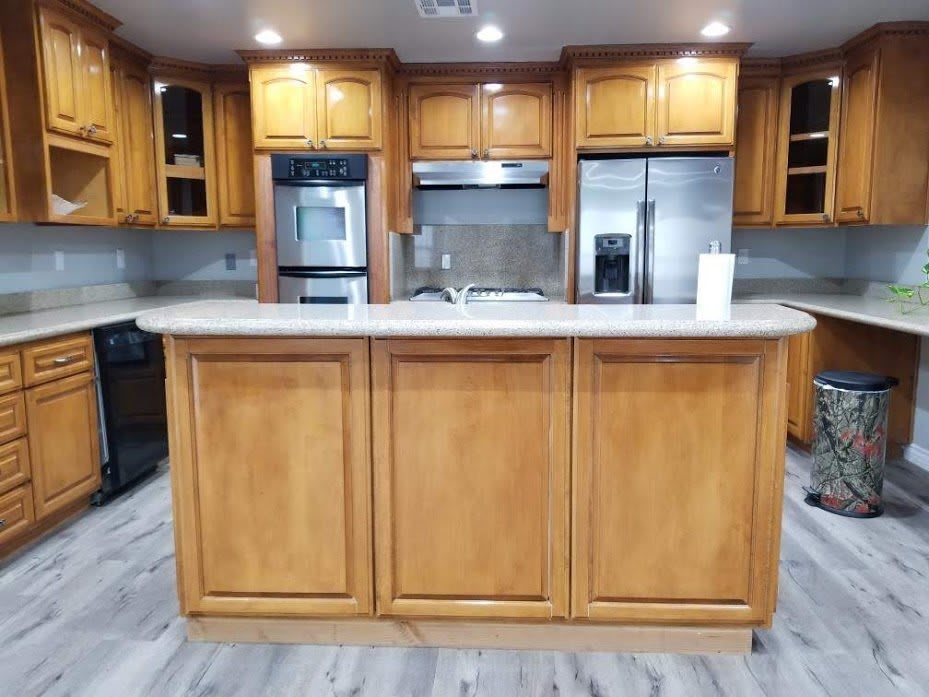 A modern kitchen with wooden cabinets and a central island, featuring appliances and a spacious countertop.