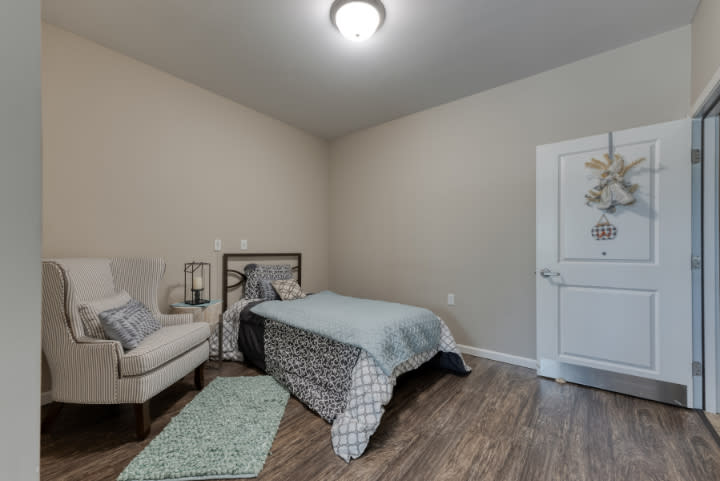 A cozy bedroom featuring a bed with patterned bedding, a comfortable chair, and tasteful decor.