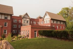 A brick residential building with multiple stories and a well-maintained lawn.