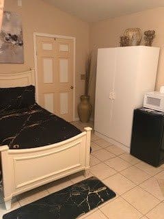 A cozy bedroom with a bed, wardrobe, microwave, and fridge.